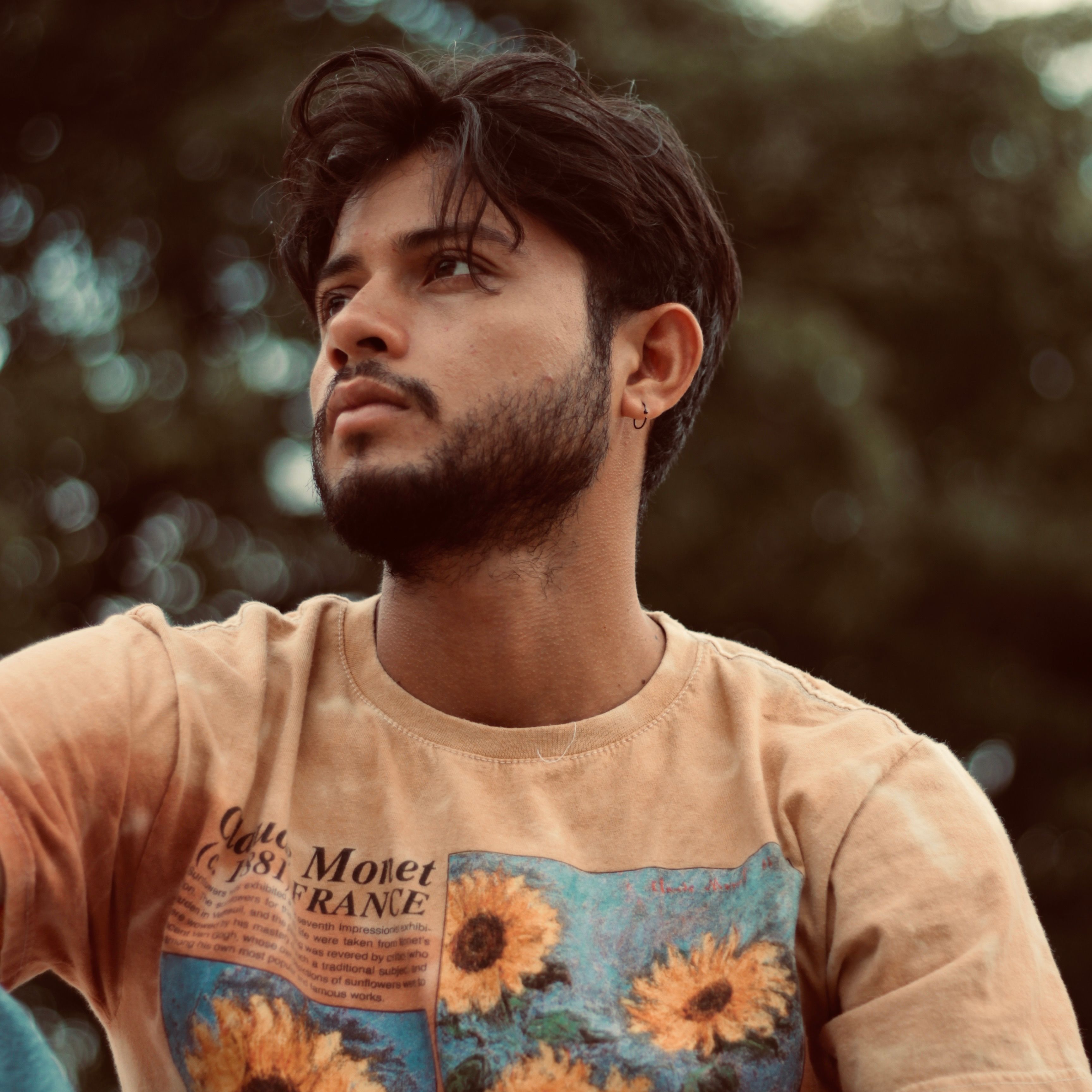 Portrait of a bearded man in a floral shirt looking thoughtfully to the side.