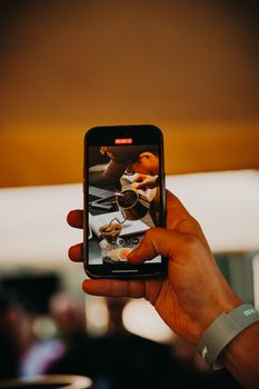 Close-up of hand holding smartphone capturing coffee preparation in Ankara, Türkiye.