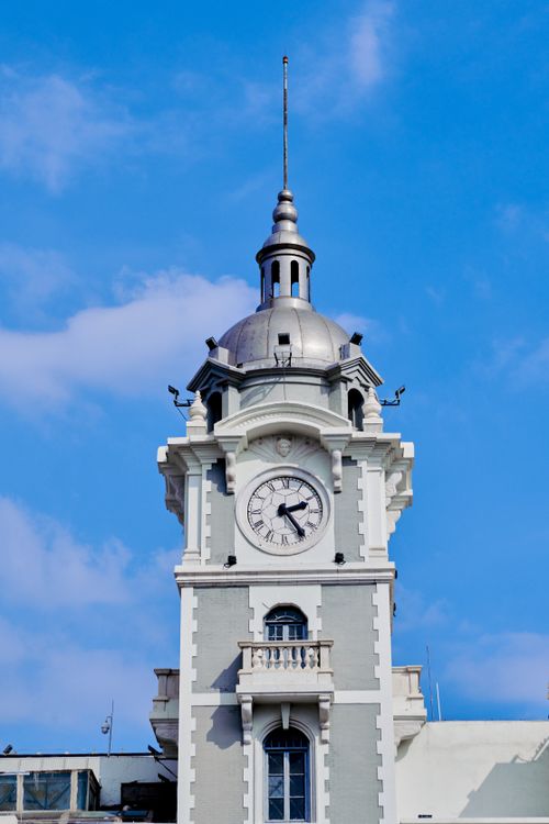 Free A classic white clock tower with intricate details stands tall against a clear blue sky. Stock Photo