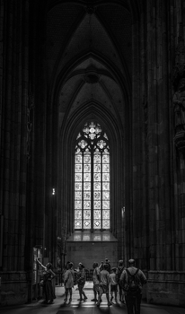 Stunning gothic cathedral interior with a large stained glass window and visitors inside.