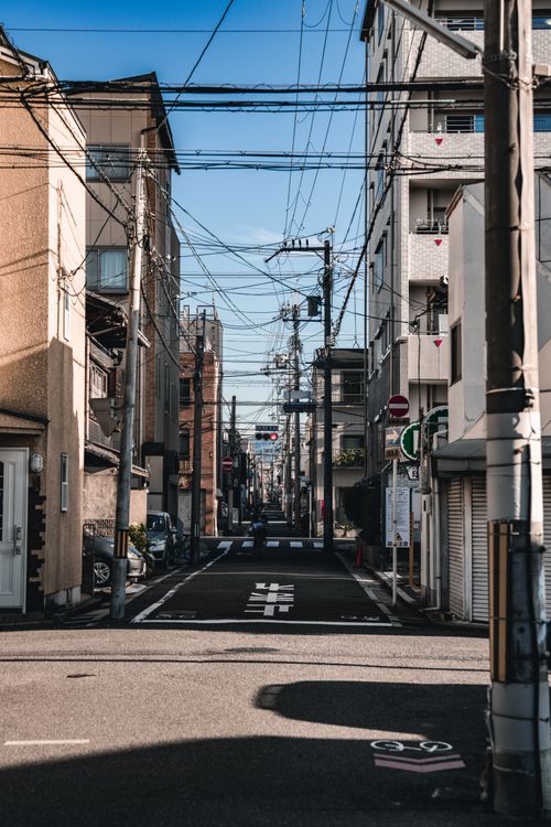 Free A quiet, narrow urban street with buildings and power lines on a sunny day. Stock Photo