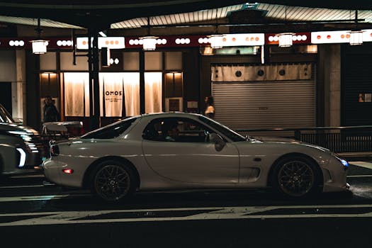 A sleek white sports car parked on a city street at night, capturing urban nightlife.