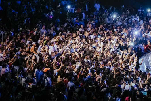 A vibrant crowd enjoying a live concert with phones raised to capture the performance.