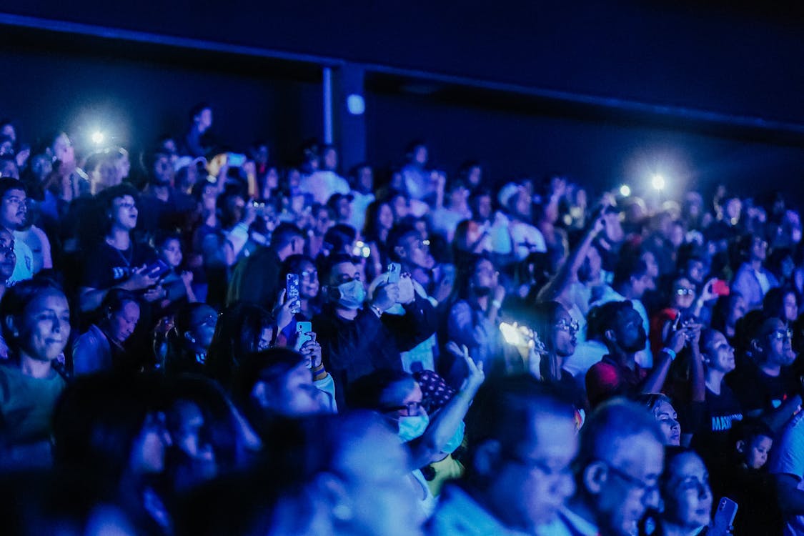 Photo of the Audience Standing with Arms Raised