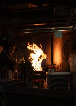 A dramatic scene of a chef managing flames in a bustling Buenos Aires kitchen.