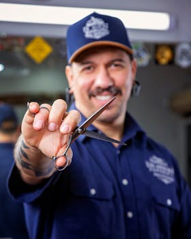 Barber smiling while holding scissors, showcasing his skills in a modern salon setting.