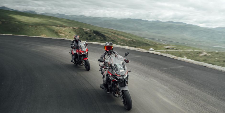 Vue de profil de la CFMoto 450 MT en mouvement sur route de montagne, en situation de balade