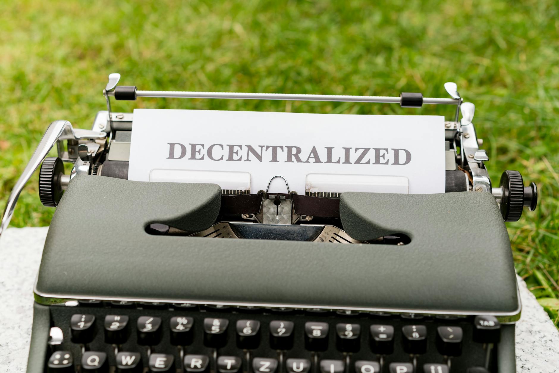 Vintage typewriter outdoors with 'Decentralized' typed paper, symbolizing old meets new in technology.