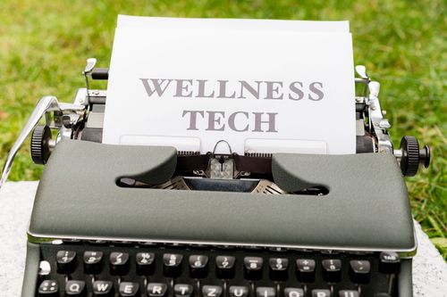 Free A retro typewriter outdoors displaying a 'Wellness Tech' message on paper. Stock Photo