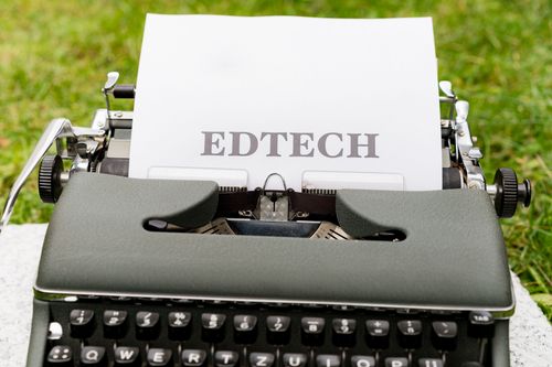 Free A vintage typewriter displays 'EdTech' on paper, set outdoors on grass. Stock Photo