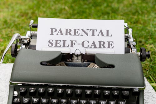 A typewriter with a paper that says parental self care