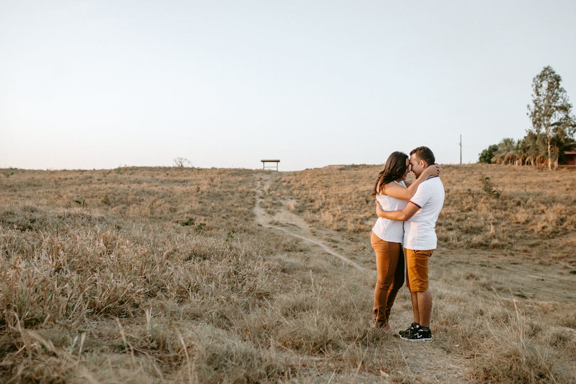 Couple Hugging At Brown Grass Field