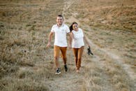 一对快乐的夫妇手牵着手，在阳光灿烂的日子里走过一片草地