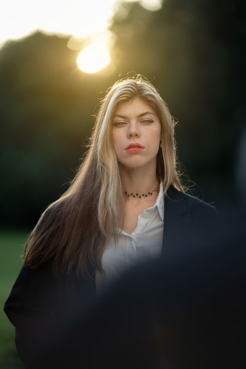 Free A striking portrait of a woman with blonde hair captured in warm sunset light, exuding grace and style. Stock Photo