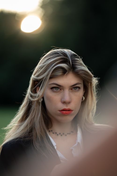 Free Close-up portrait of a woman with blonde hair, softly lit by sunlight outdoors. Stock Photo