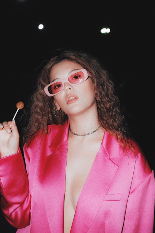 Young Woman in a Pink Blazer Holding a Lollipop