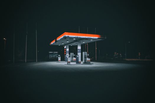 A gas station at night with a red and orange sign