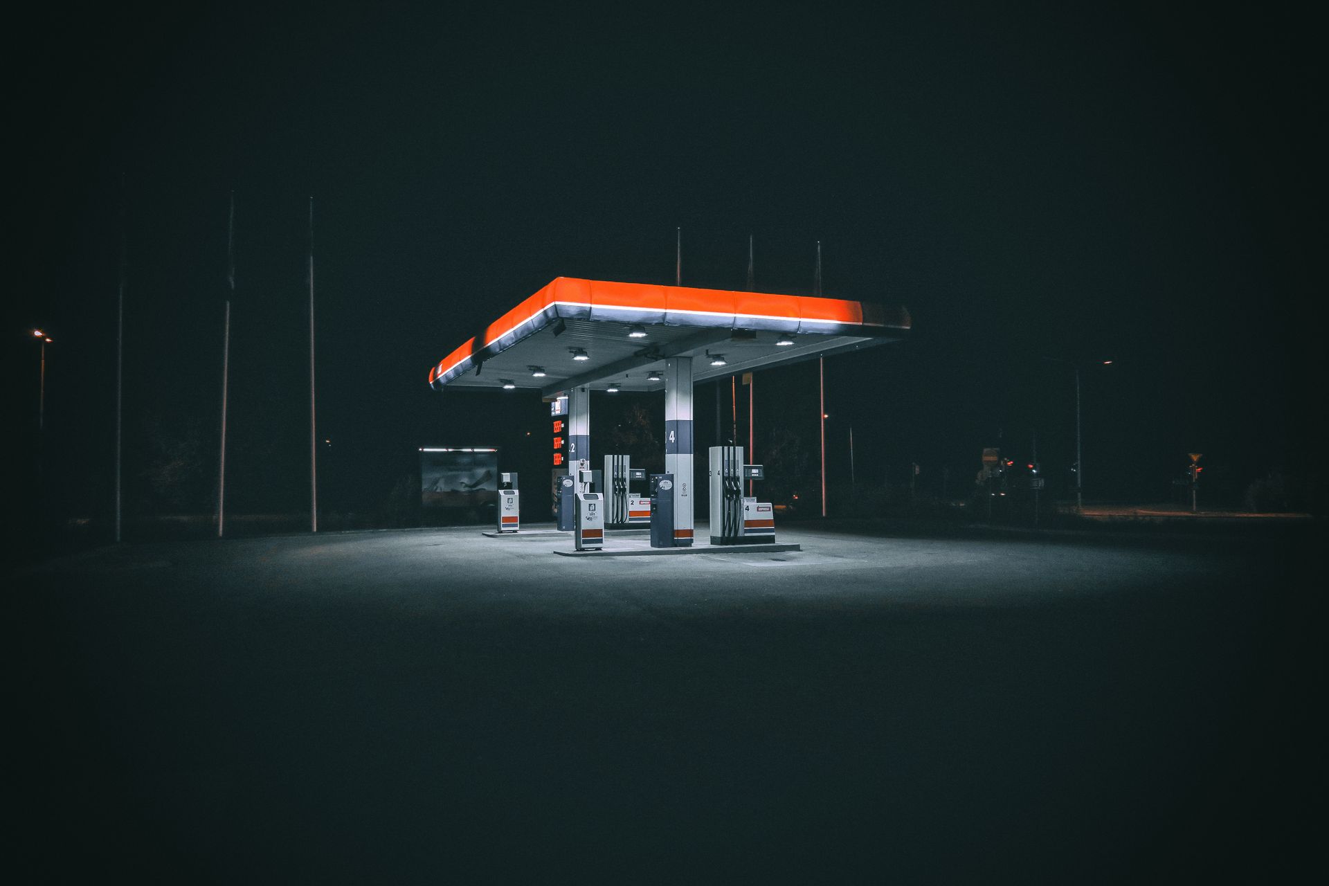 A gas station at night with a red and orange sign