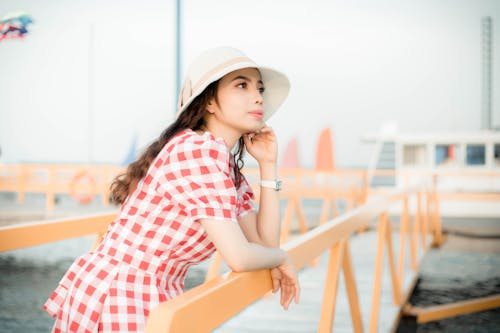 女人在碼頭上穿紅白色的泡泡袖連衣裙的選擇性聚焦攝影