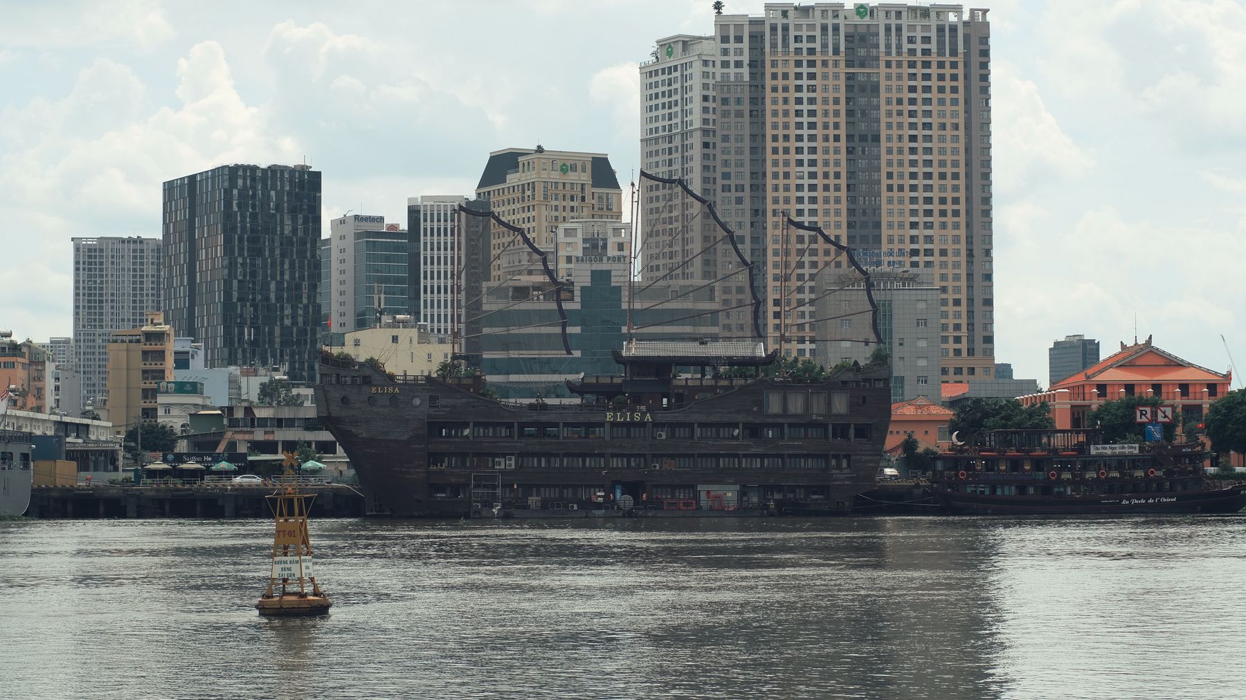 Skyline of Saigon with ships and modern buildings against a cloudy sky, reflecting urban life.