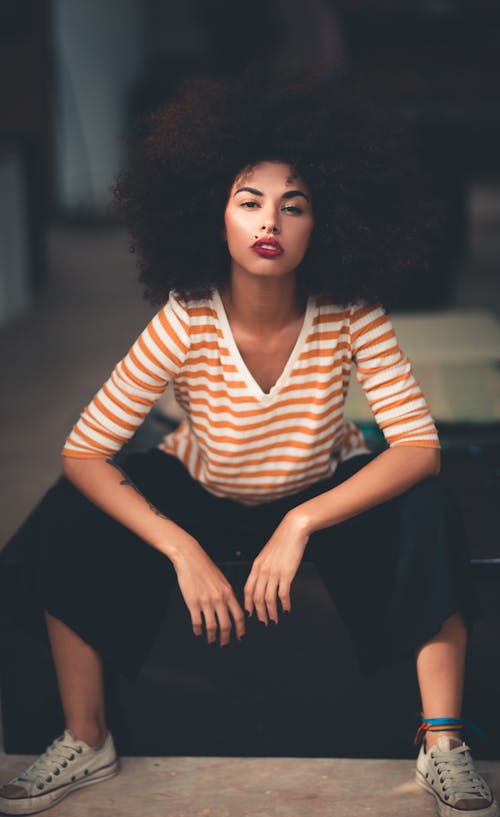 Free Woman Sitting Wearing Orange And White V-neck Striped Elbow Sleeved Shirt  Stock Photo