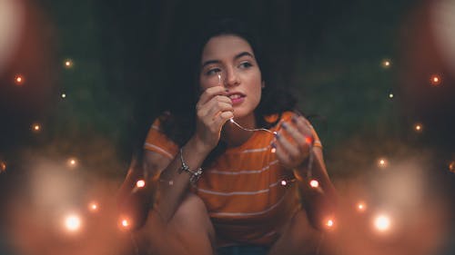 Woman Wearing Orange And White Striped Shirt Holding String Lights
