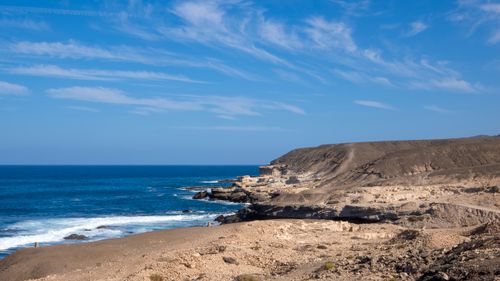 Free A breathtaking view of a rocky coastline with clear blue skies and ocean waves rolling in. Stock Photo