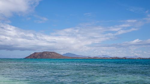 Free A scenic view of the ocean with a distant island and clear blue sky. Stock Photo