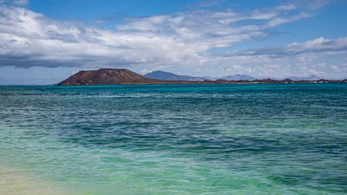 Free Breathtaking view of an island's coastline with clear blue waters and lush hills under a vast sky. Stock Photo