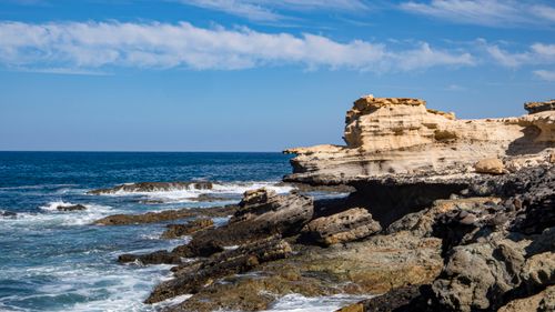 Free A stunning view of rugged coastal cliffs with waves crashing beneath a clear blue sky. Stock Photo