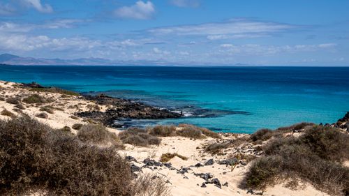 Free Serene beach landscape featuring turquoise waters and rocky shores, perfect for summer travel inspiration. Stock Photo