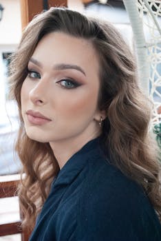 Close-up portrait of a woman with elegant makeup and wavy hair in a soft light setting.