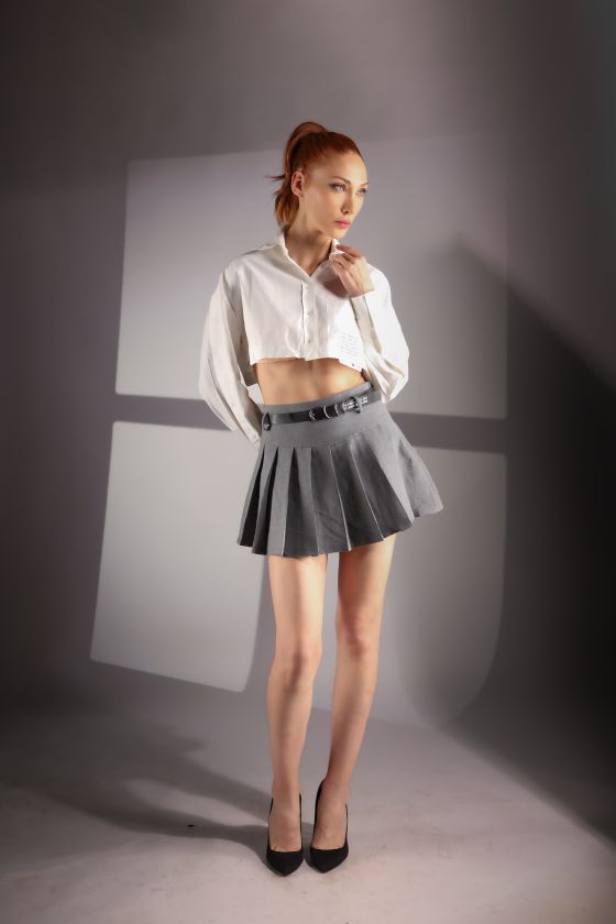 Model in a grey pleated skirt against a grey backdrop, photo by Oben Kural on Pexels