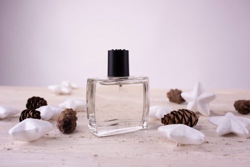Free A stylish perfume bottle surrounded by pine cones and star shapes on a wooden surface. Stock Photo