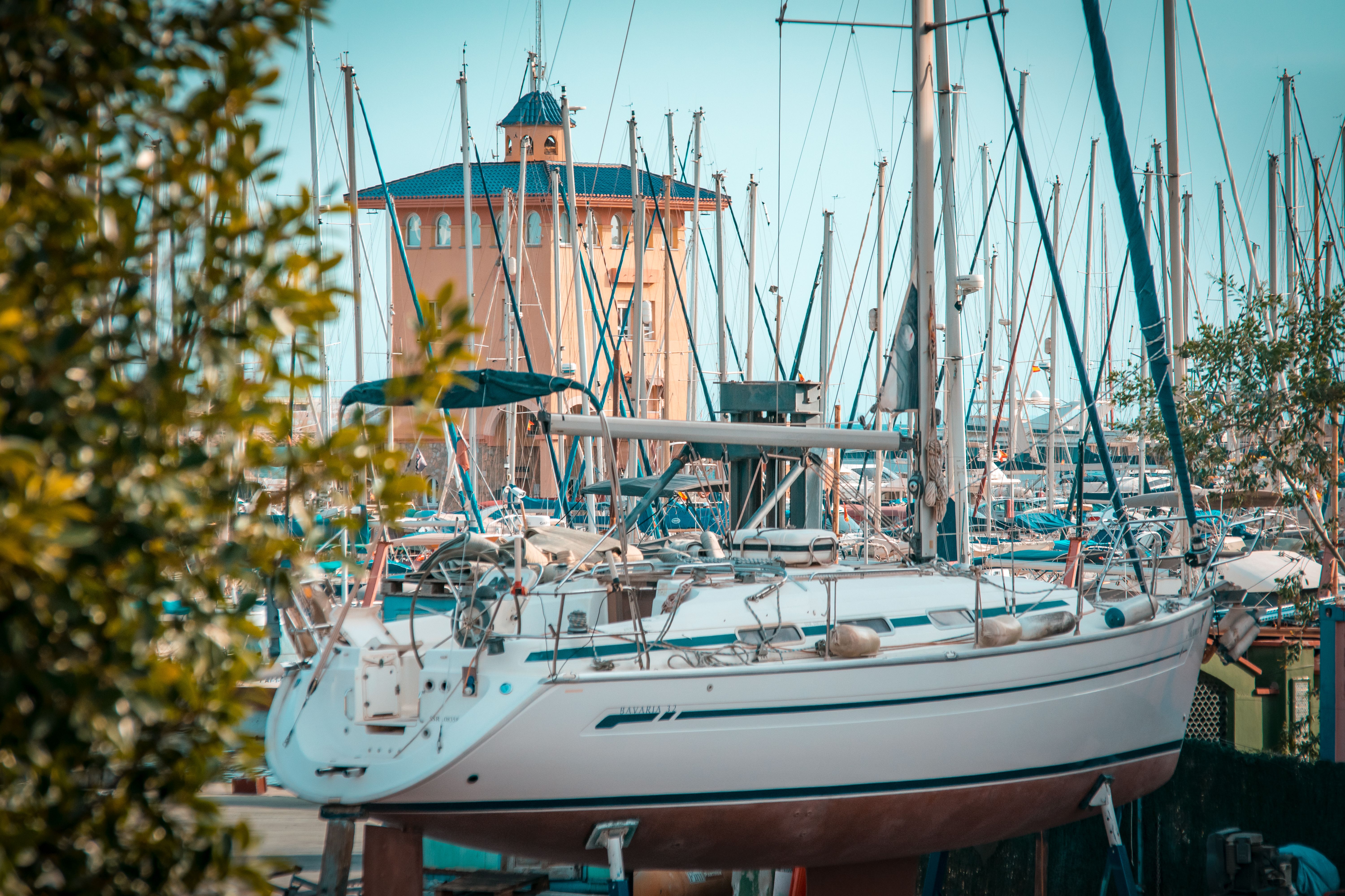 A serene view of sailboats docked at a marina in Torrevieja, Spain, with a scenic tower backdrop.