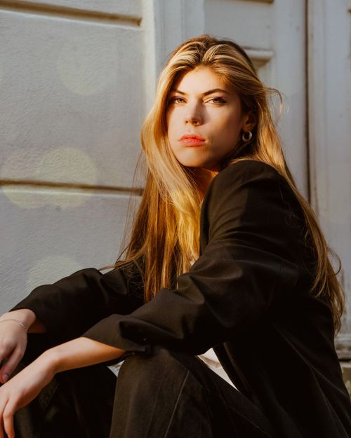 Free Young woman in a black suit posing confidently outdoors, exuding elegance and style. Stock Photo