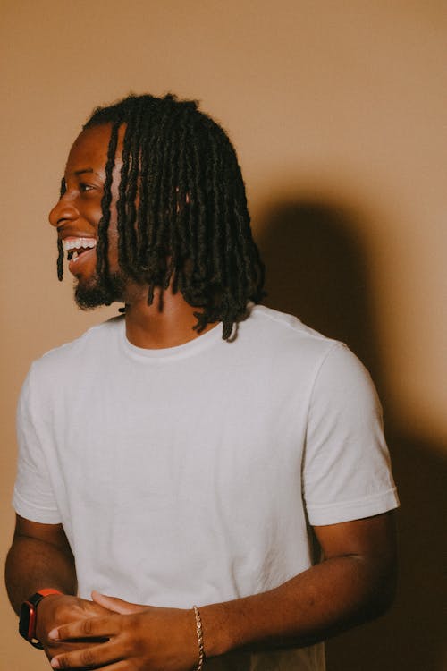 Smiling Young Black Man with Dreadlocks Posing in Studio