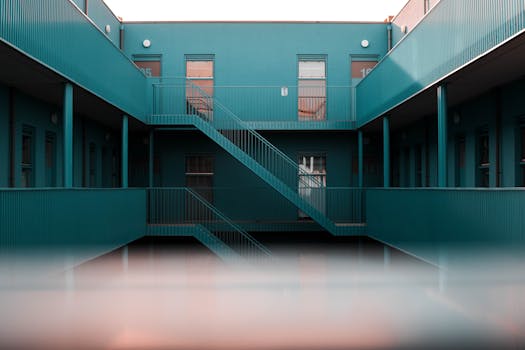 Modern interior view of a blue apartment complex featuring staircases and doors.