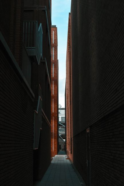 A narrow urban alleyway flanked by tall brick buildings, offering a unique city perspective.
