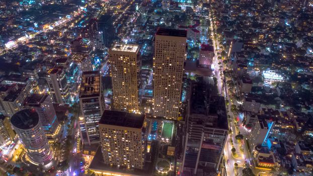 A stunning aerial view of Mexico City at night, showcasing illuminated skyscrapers and bustling urban life.