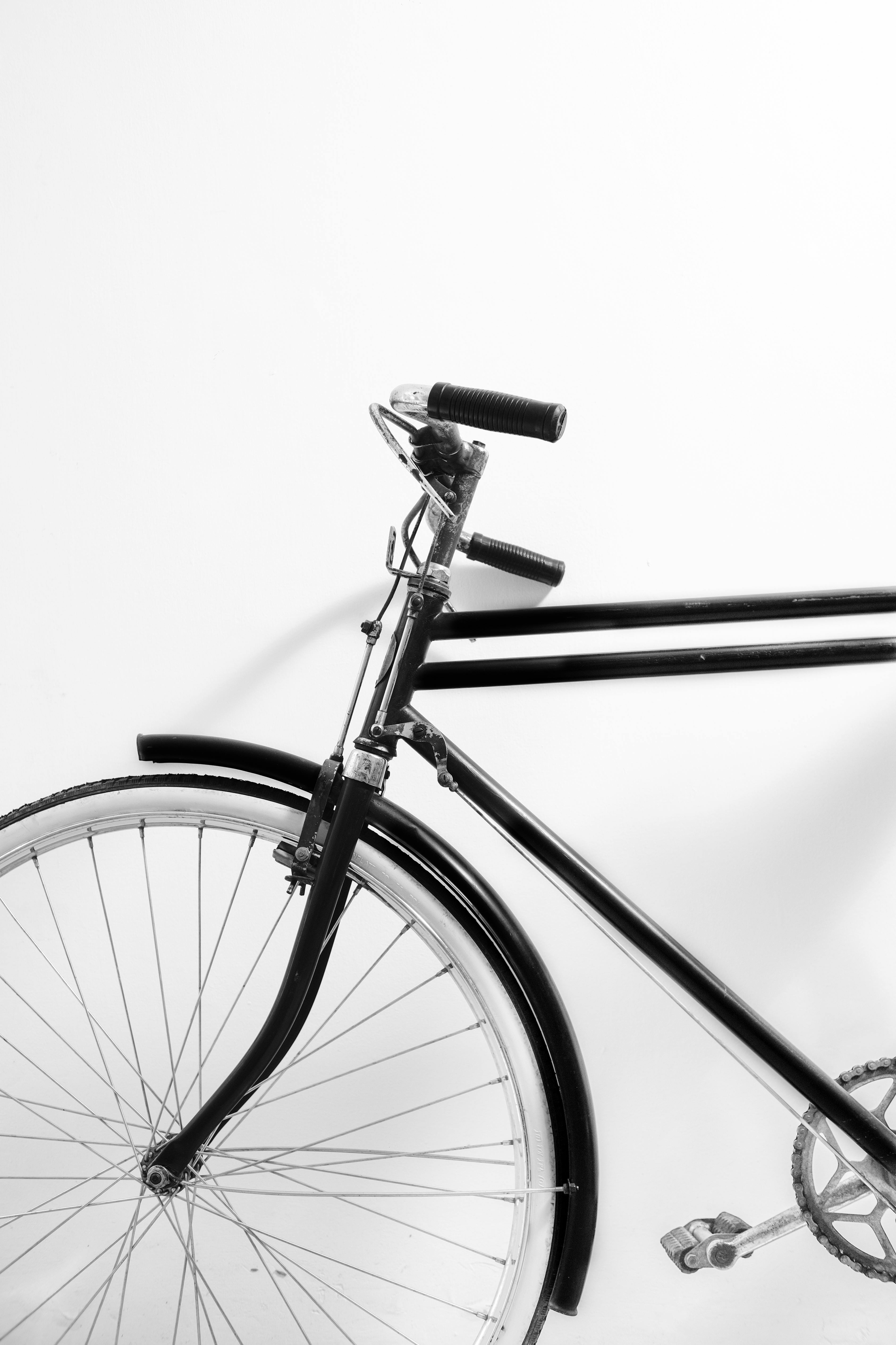 Artistic black and white image of a vintage bicycle against a white wall.