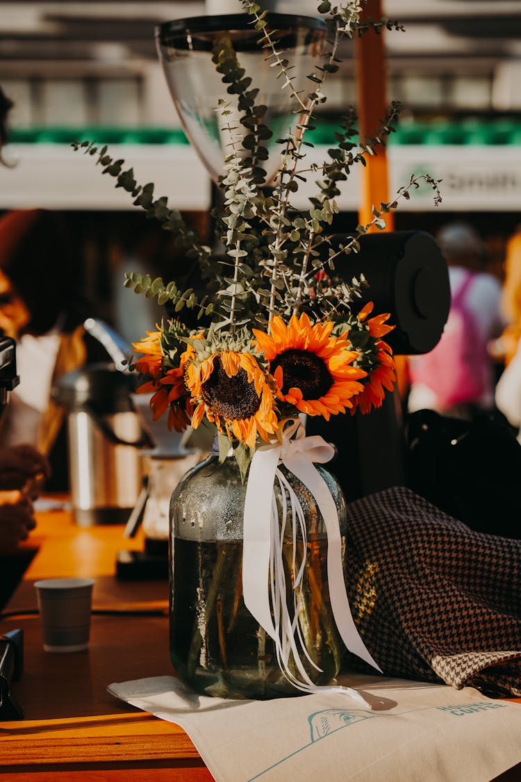 Bouquet With Sunflowers In Glass Vase On Restaurant Table