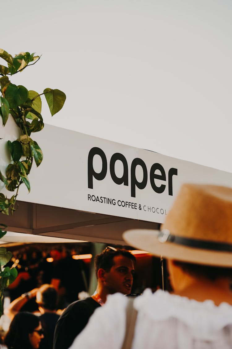 People Walking Under Cafe Sign