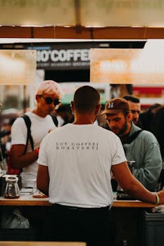 Back view of a barista in a busy coffee shop with patrons in Ankara, Türkiye.