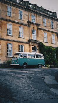 Classic turquoise van parked in front of a historic urban building showcasing a retro vibe.