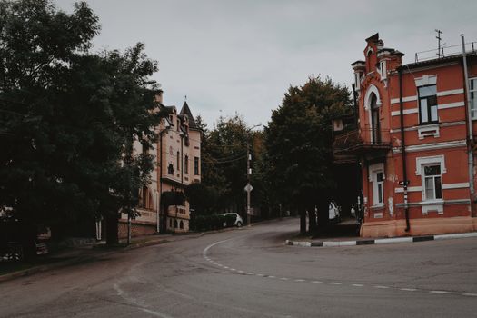 A picturesque view of a curved street featuring historical urban architecture with lush trees.