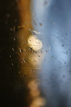 Close-up of raindrops on a window with a blurred background in warm evening light.