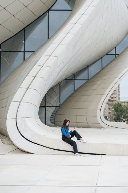 Woman sitting on modern architecture in Baku, Azerbaijan. Stylish and serene urban scene.