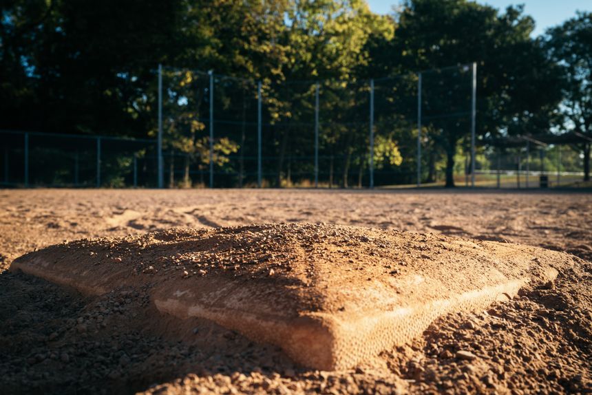 A base on the dirt of an empty ballfield in low evening sun — photo by Chris F on Pexels