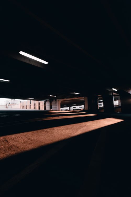 Free A dramatic capture of shadows in an urban underground parking structure with architectural elements. Stock Photo